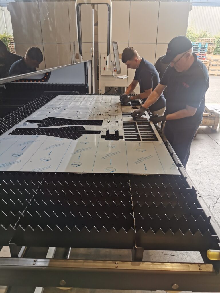 Team members operating the Bodor fiber laser machine in the workshop